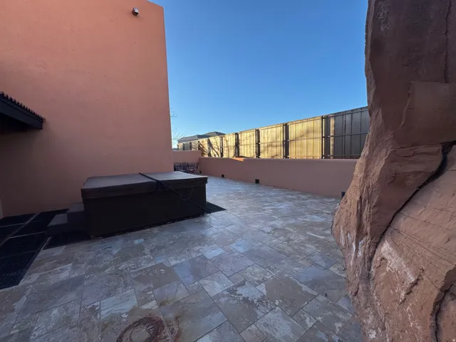 Fenced backyard featuring a hot tub and a large patio area