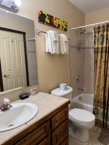 Bathroom featuring vanity, shower / bath combo, and light tile patterned floors