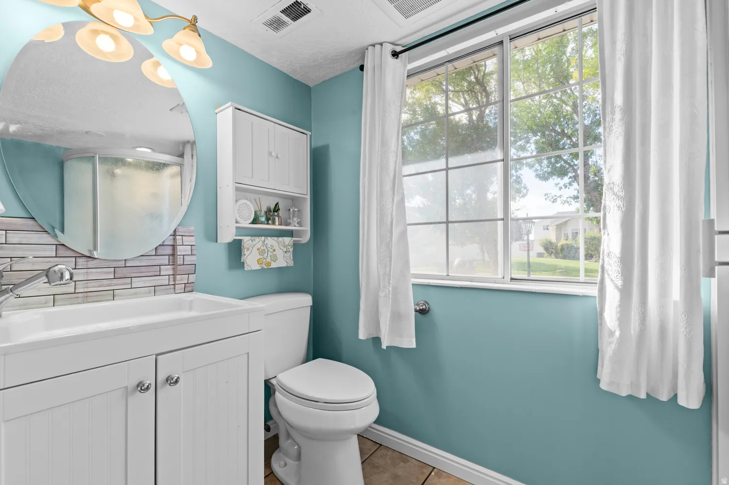 Bathroom with vanity, backsplash, light tile patterned flooring, and a shower