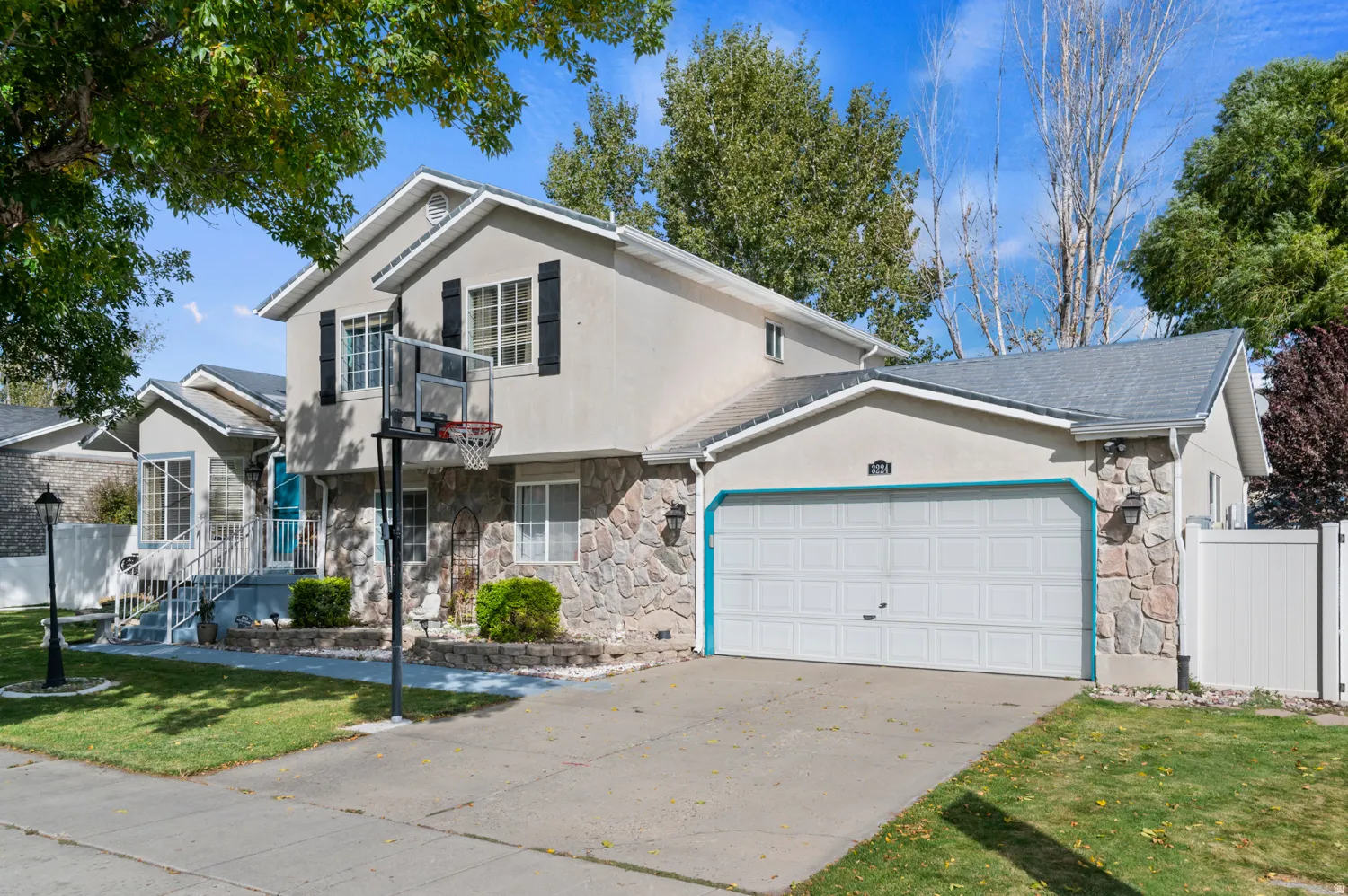 View of front of house with stone siding, an attached garage, driveway, and stucco siding