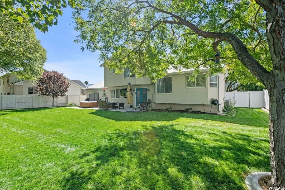 Rear view of property with a fenced backyard, a patio, stucco siding, a hot tub, and an outdoor hangout area