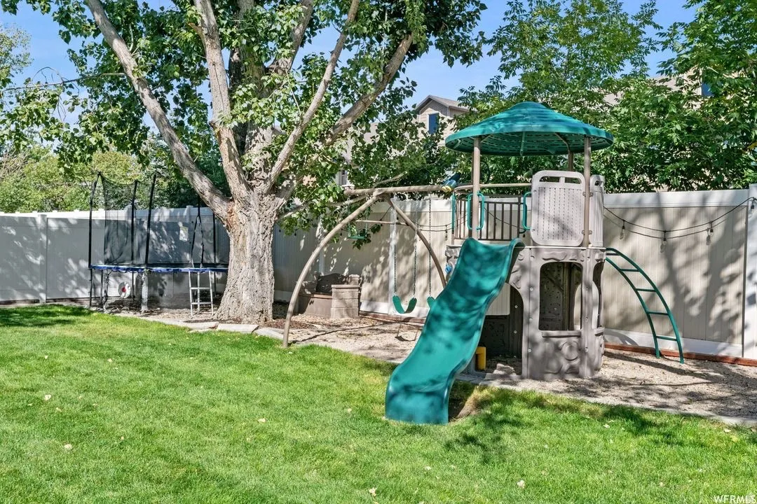 Communal playground with a trampoline and a fenced backyard