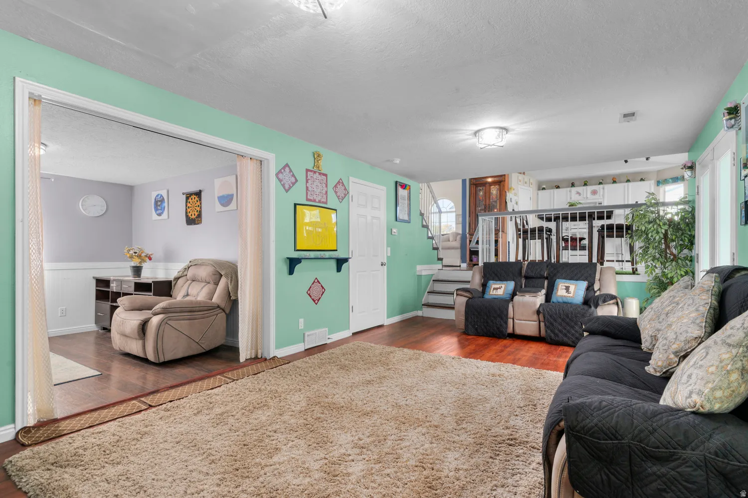 Living room with stairs, a textured ceiling, and dark wood-style floors