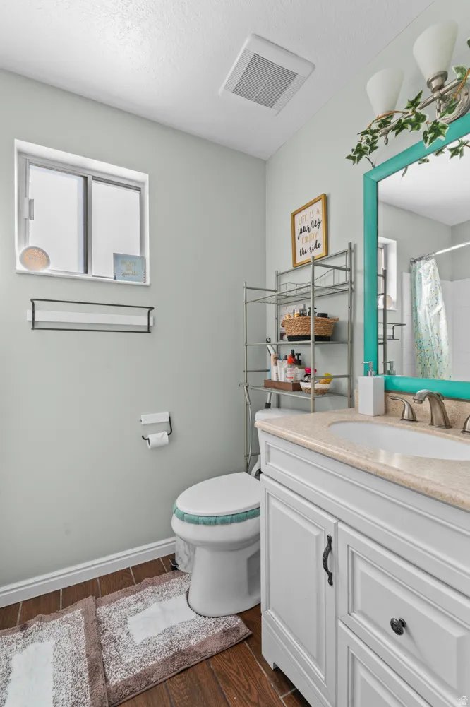 Full bathroom featuring vanity, dark wood-style flooring, a shower with curtain, and a textured ceiling