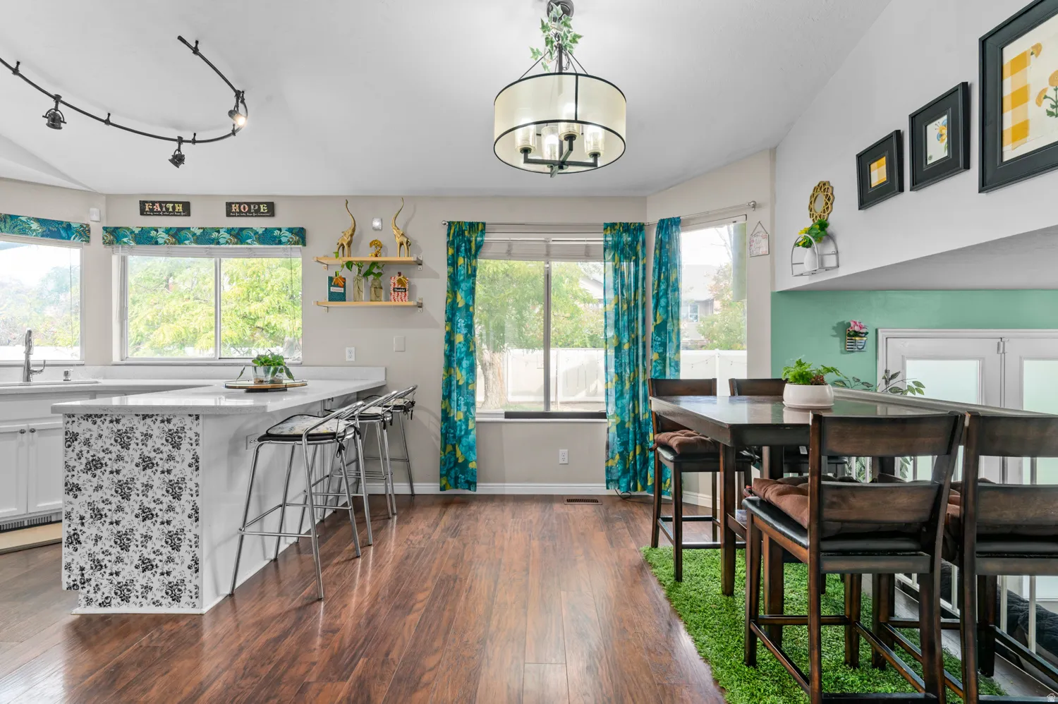Dining area featuring dark wood-type flooring, plenty of natural light, track lighting, and a chandelier