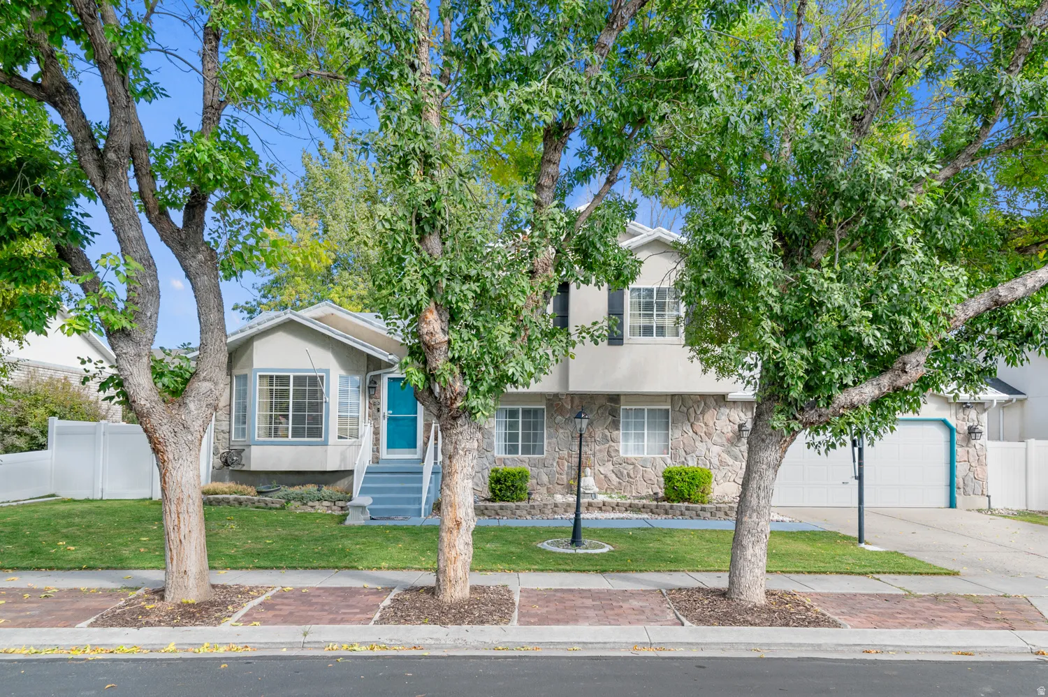 View of front of home featuring stone siding, stucco siding, driveway, and a garage