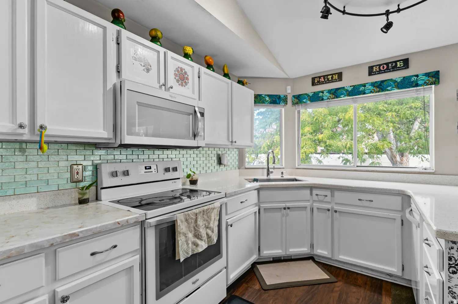 Kitchen with white appliances, white cabinetry, dark wood finished floors, light stone countertops, and decorative backsplash