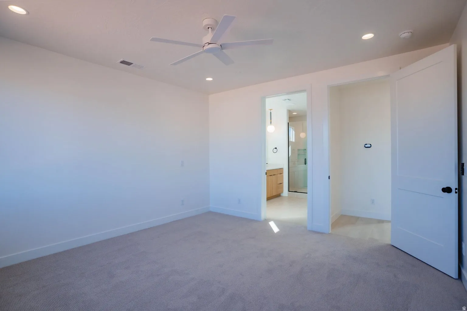 Unfurnished bedroom featuring recessed lighting, light carpet, a ceiling fan, and ensuite bathroom