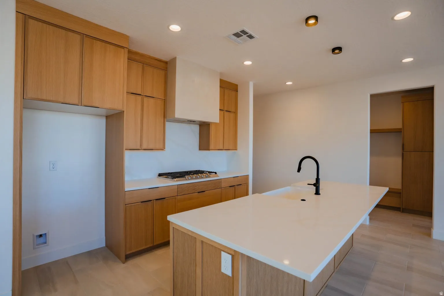 Kitchen with modern cabinets, recessed lighting, a center island with sink, light stone counters, and stainless steel gas cooktop