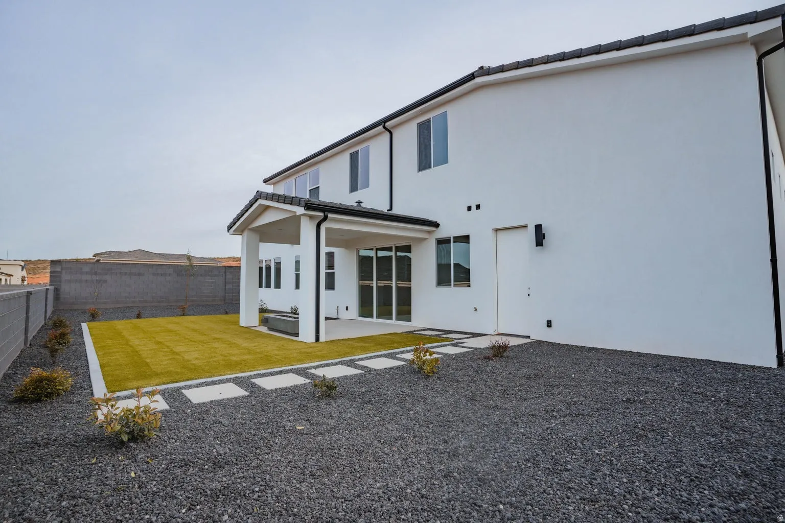 Rear view of house featuring a patio area, stucco siding, and a fenced backyard