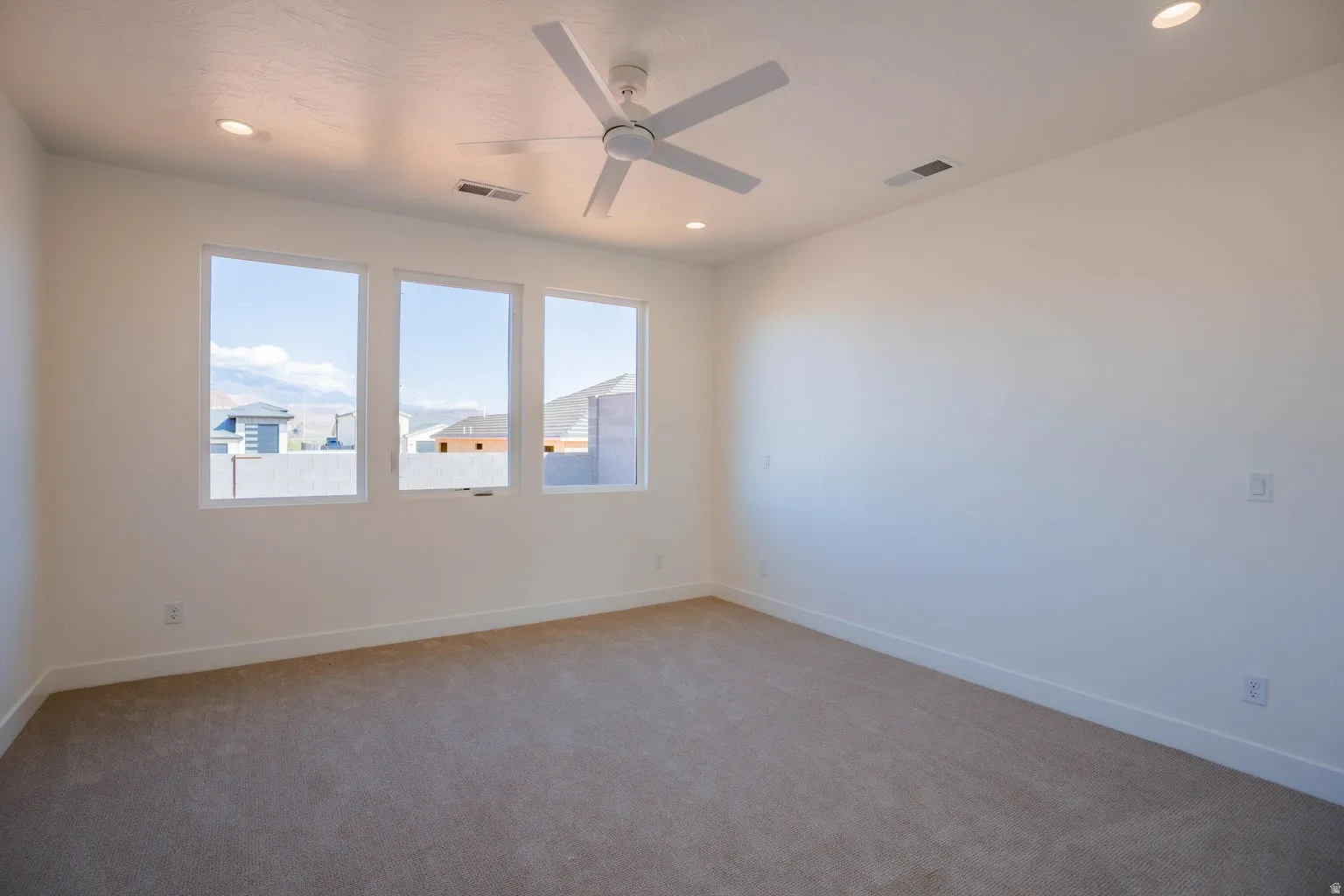 Empty room with light colored carpet, a ceiling fan, and recessed lighting