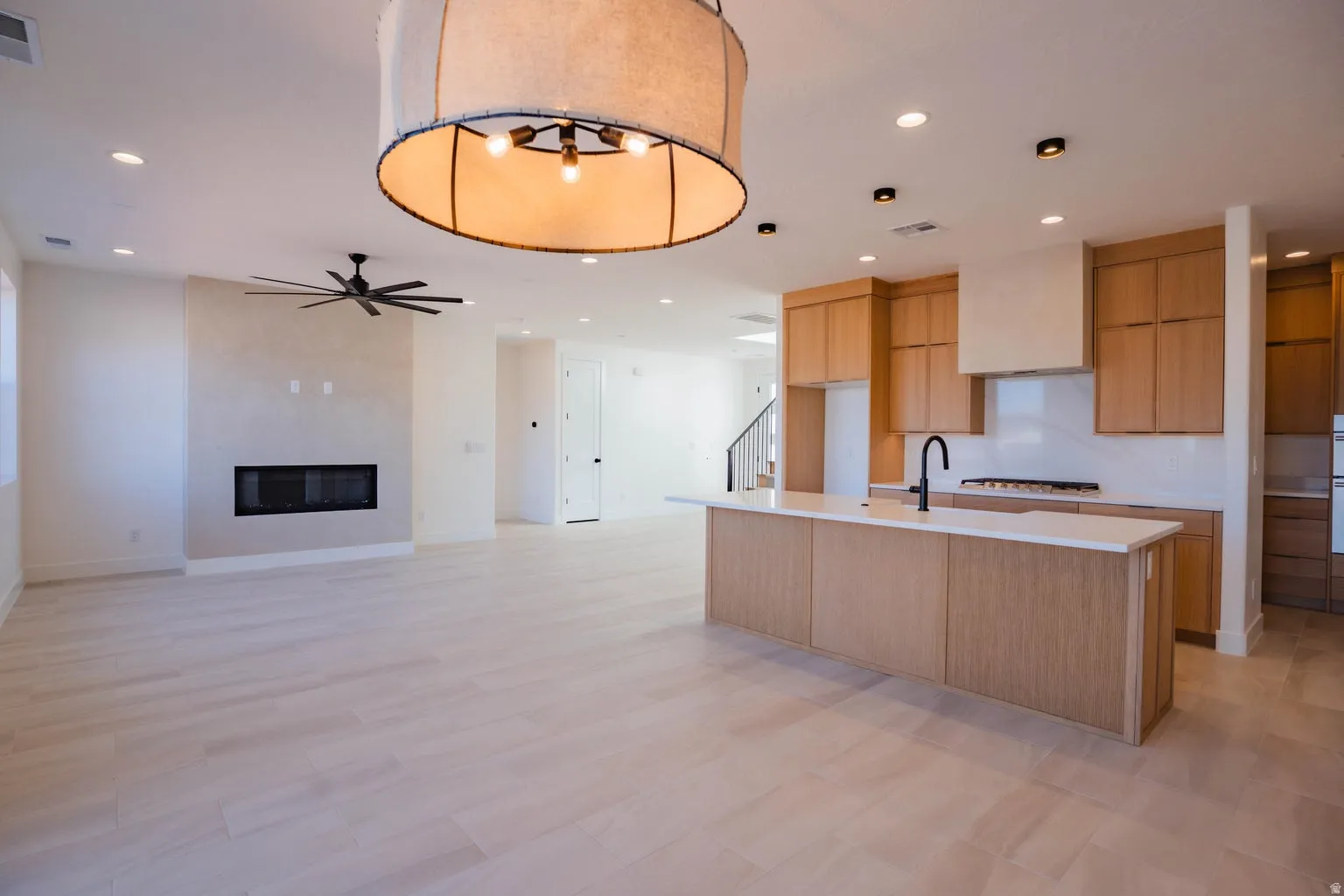 Kitchen with modern cabinets, recessed lighting, an island with sink, open floor plan, and a fireplace