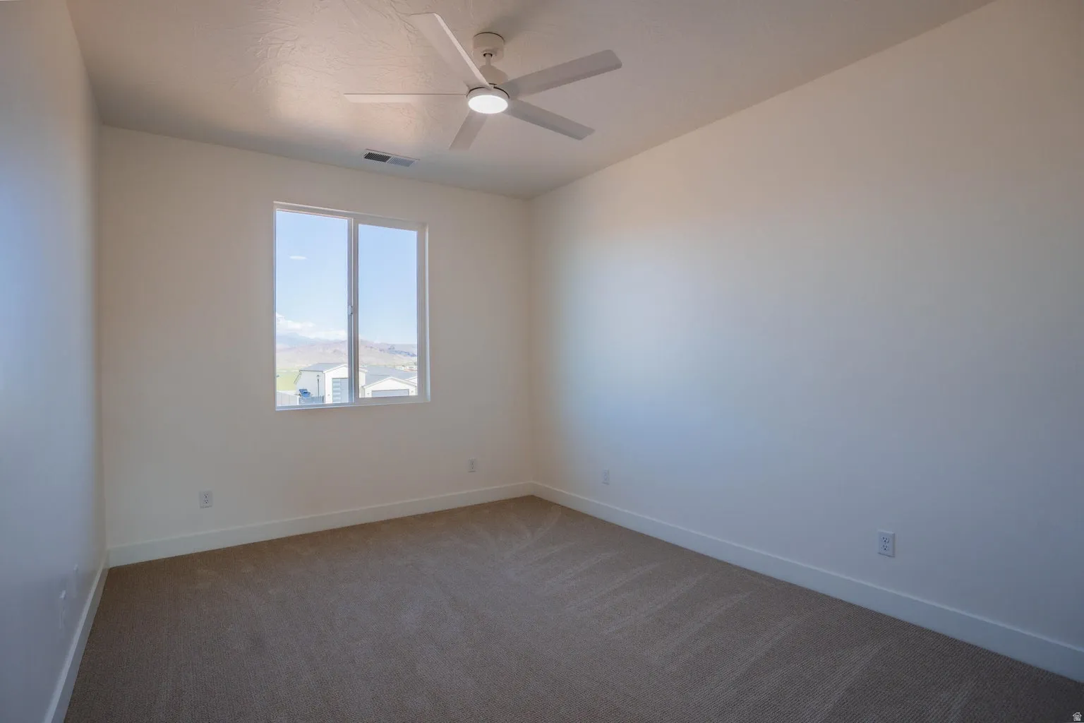 Carpeted spare room with baseboards and ceiling fan