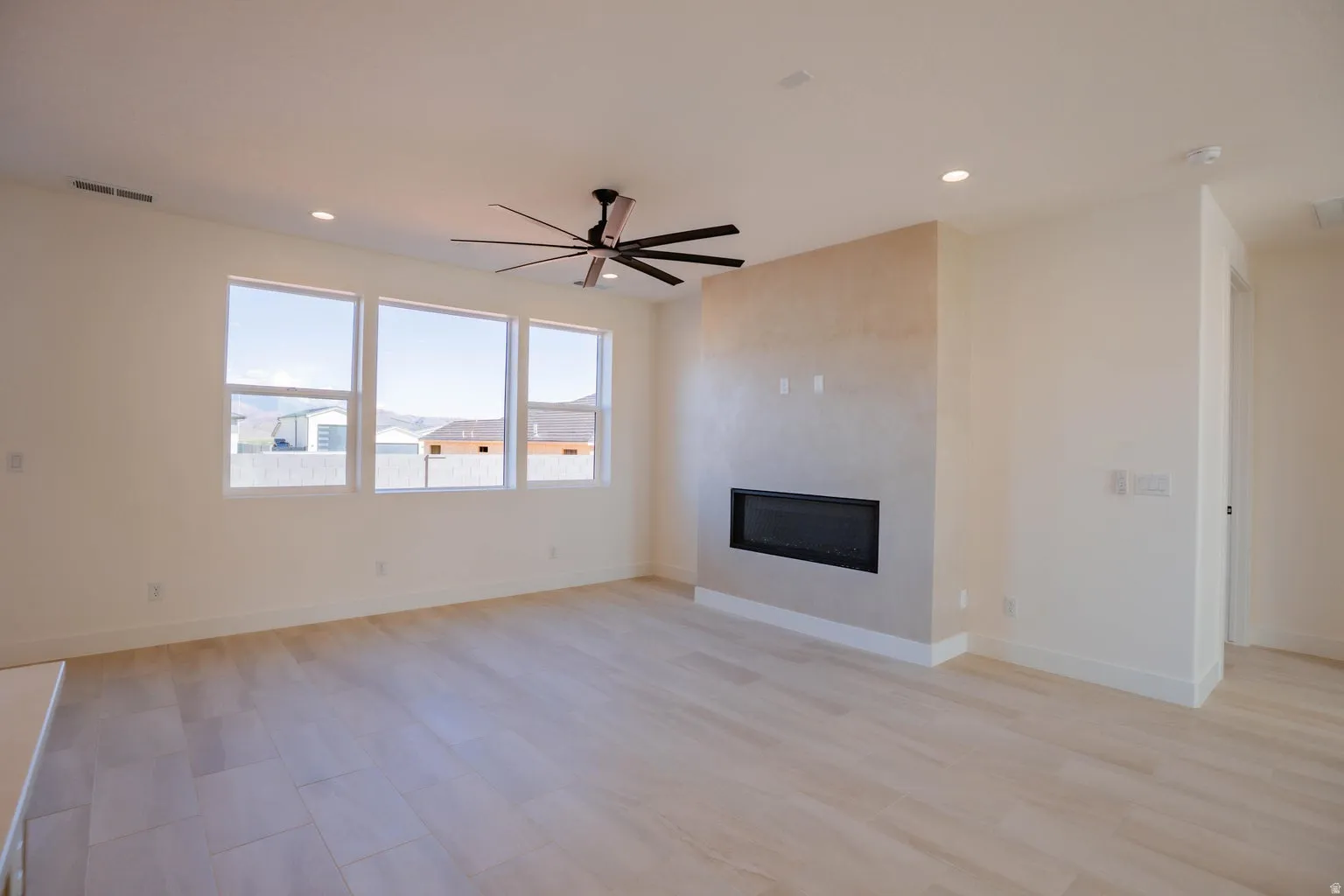 Unfurnished living room featuring a glass covered fireplace, recessed lighting, and ceiling fan