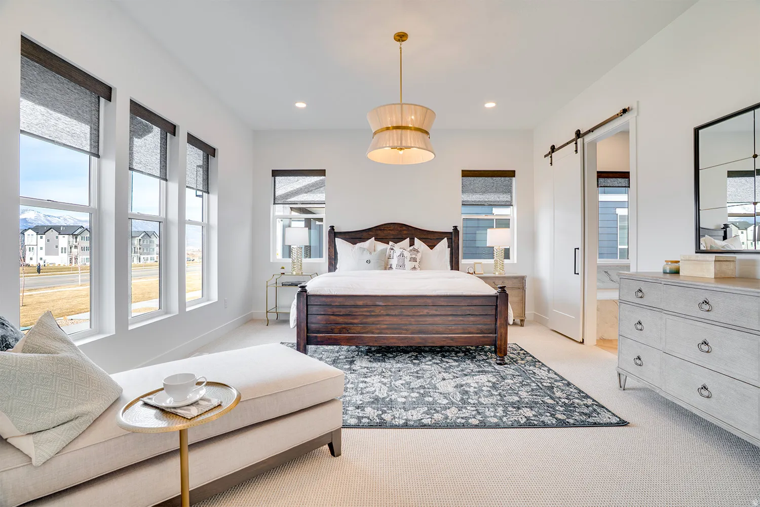 Bedroom with a barn door, light carpet, recessed lighting, and ensuite bathroom