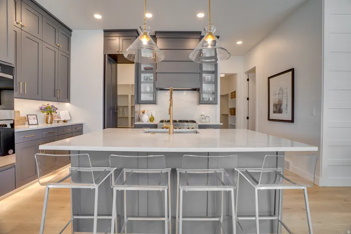 Kitchen with gray cabinetry, light wood finished floors, pendant lighting, light stone counters, and recessed lighting