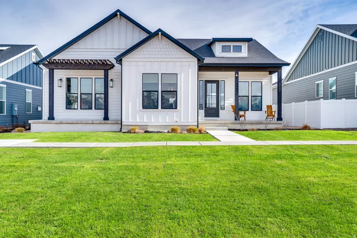 Modern farmhouse with board and batten siding, a front yard, a porch, and roof with shingles