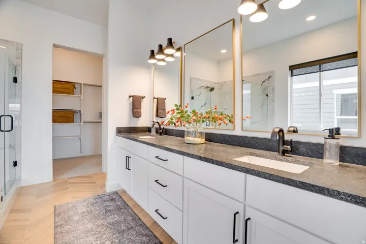 Full bathroom with a marble finish shower, double vanity, and a walk in closet