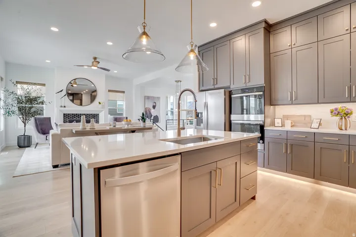 Kitchen with stainless steel appliances, open floor plan, gray cabinets, light wood-type flooring, and recessed lighting