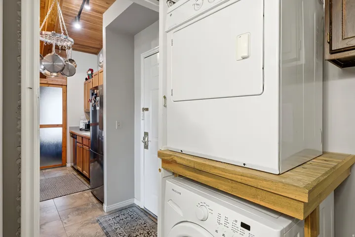 Washroom featuring wooden ceiling and stacked washer and clothes dryer