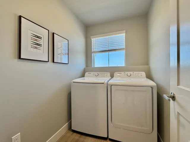 Laundry room with washing machine and clothes dryer and light wood finished floors