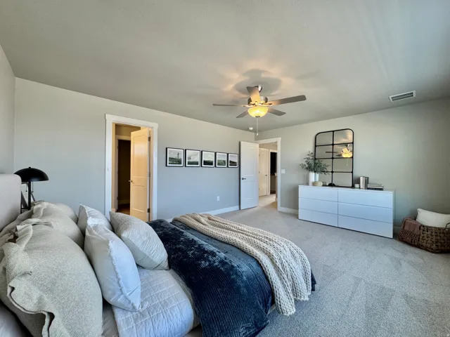 Carpeted bedroom with a ceiling fan and baseboards