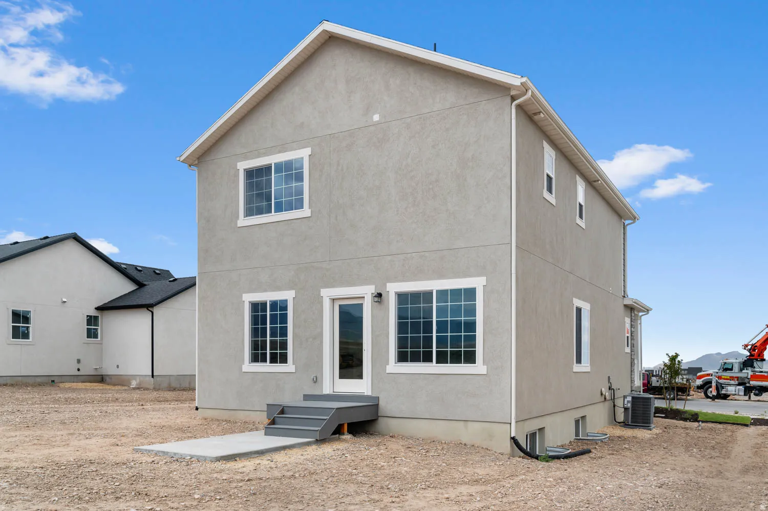 Two-story stucco exterior with white trim windows and a rear entry door
