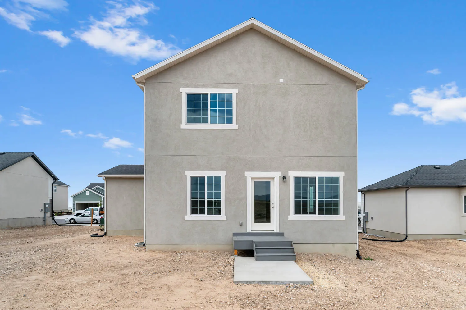 Rear exterior showcasing a neutral stucco finish and white trim