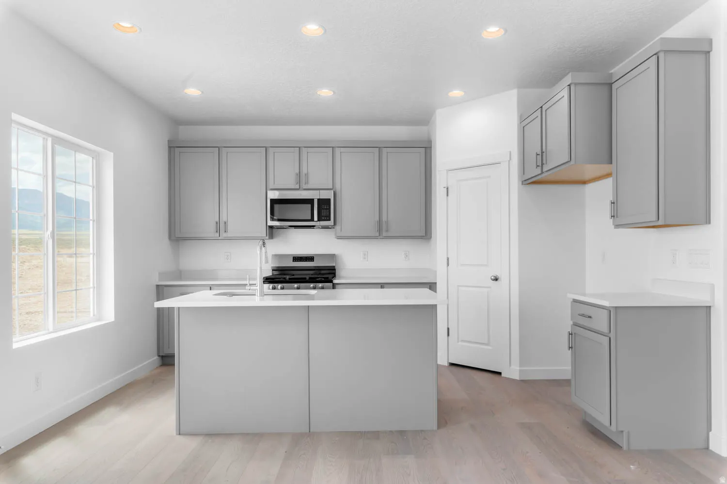 Modern kitchen featuring light gray cabinetry, white countertops, and stainless steel appliances