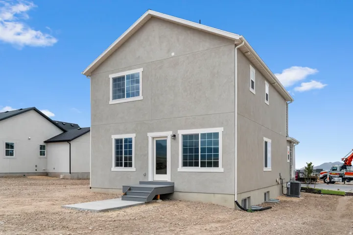 Two-story stucco exterior with white trim windows and a rear entry door
