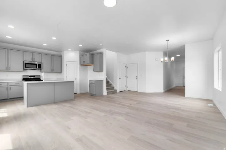 Open-concept living space featuring light wood-finish flooring, recessed lighting, and a modern chandelier