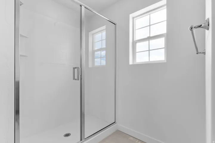 Shower enclosure with clear glass door, chrome hardware, white subway tile shower surround, and built-in shelving