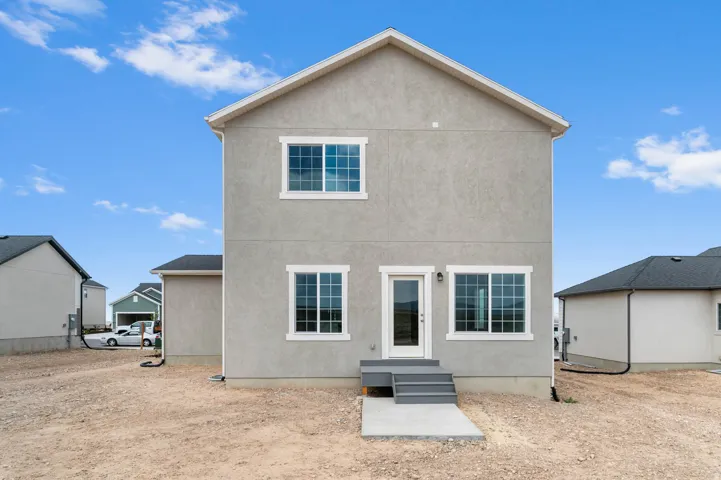 Rear exterior showcasing a neutral stucco finish and white trim