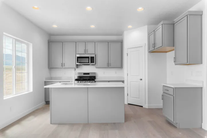 Modern kitchen featuring light gray cabinetry, white countertops, and stainless steel appliances