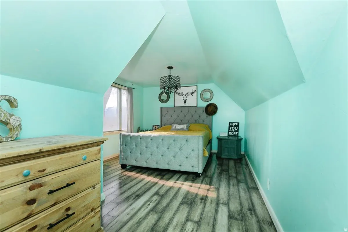 Bedroom with dark wood-style flooring and lofted ceiling