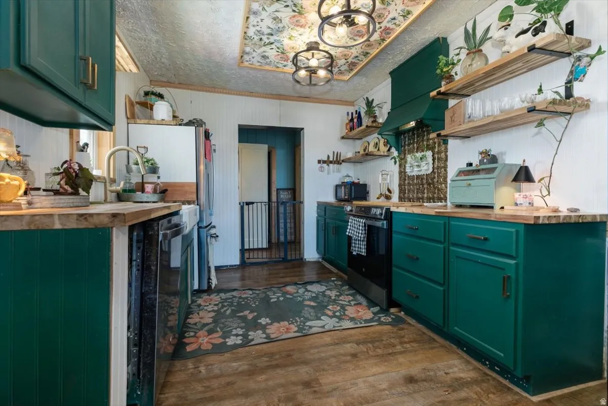 Kitchen with green cabinets, wooden counters, open shelves, black appliances, and dark wood finished floors