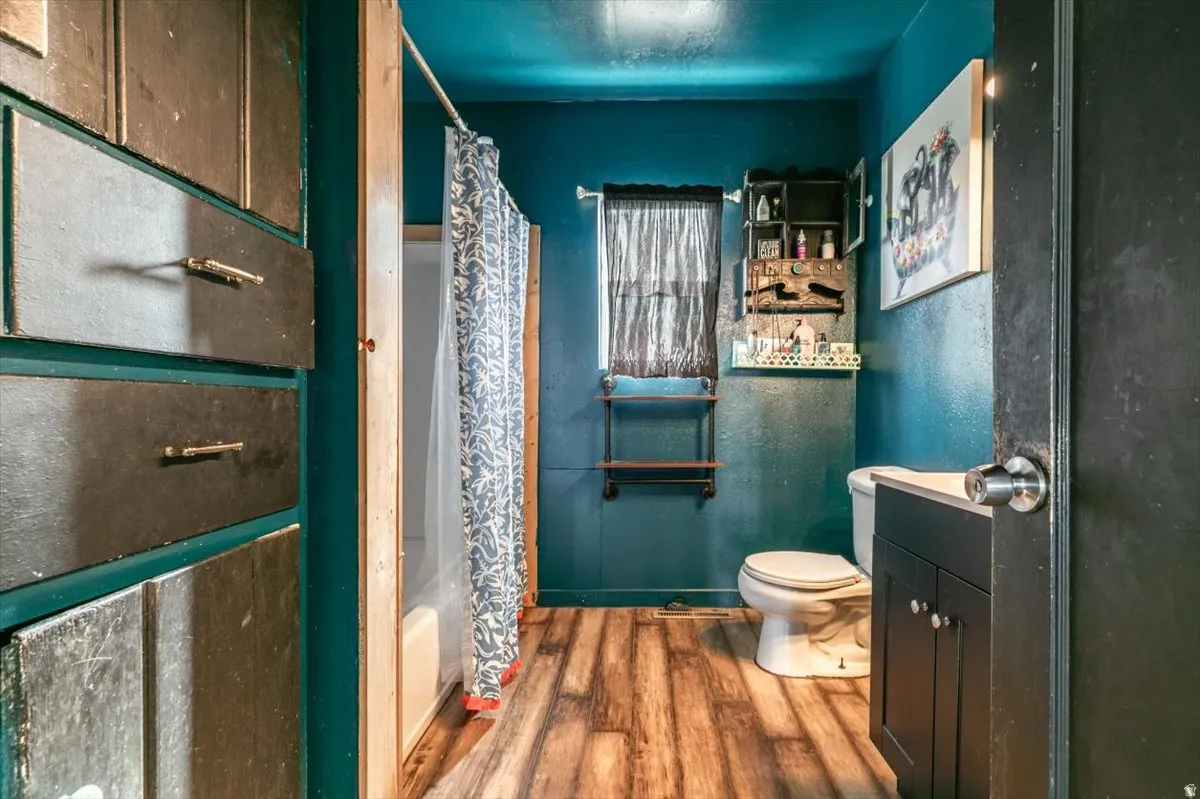 Full bath featuring dark wood finished floors, shower / bath combo, and vanity