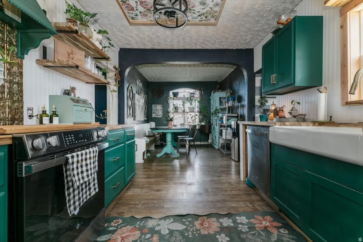 Dual tone kitchen featuring arched walkways, electric range oven, dark wood-type flooring, stainless steel dishwasher, and a textured ceiling