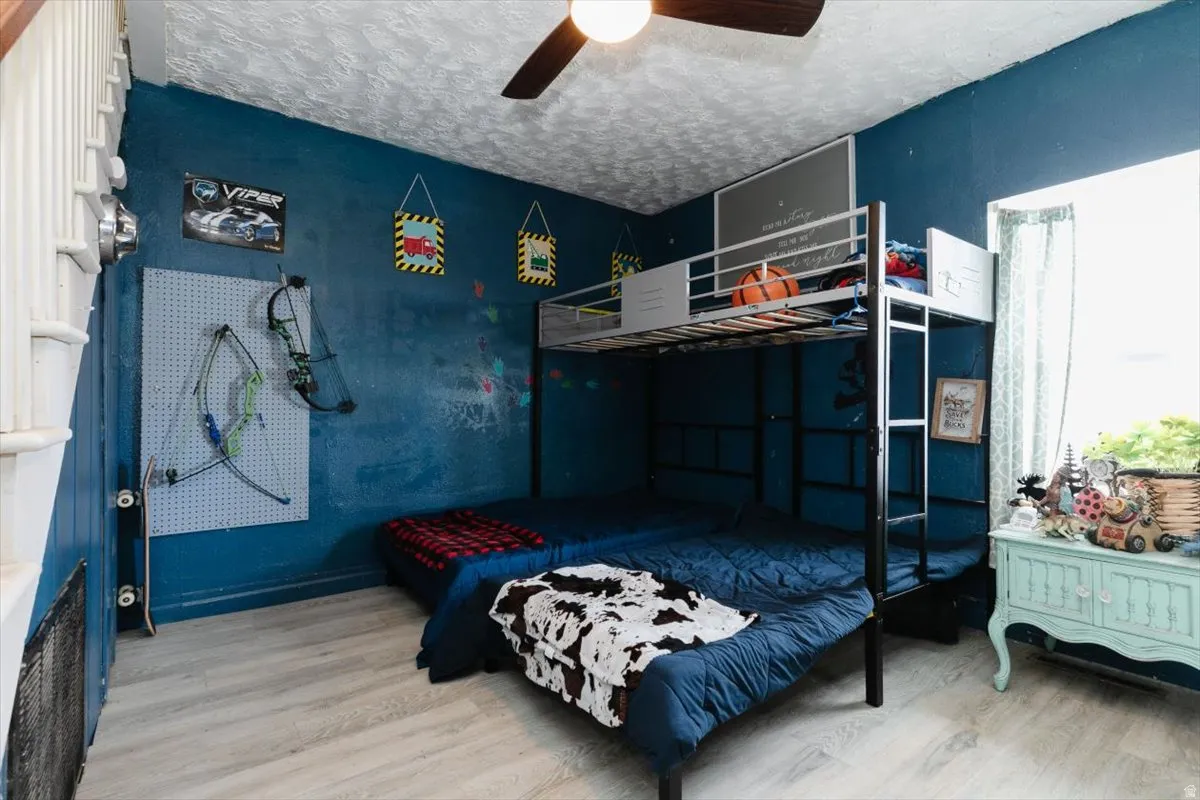 Bedroom with light wood-style flooring, a ceiling fan, and a textured ceiling