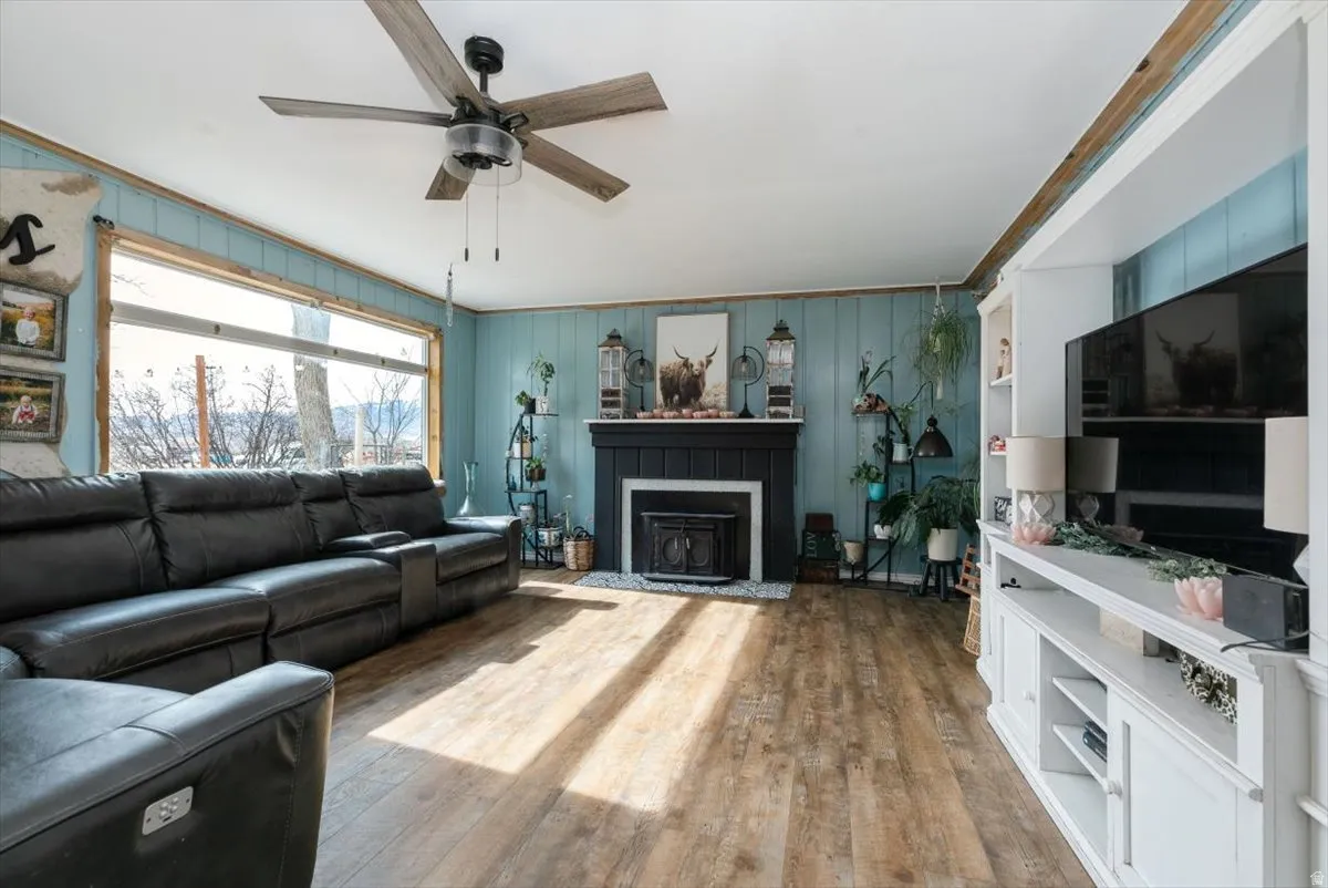 Living room featuring hardwood / wood-style flooring, ceiling fan, and a fireplace with flush hearth