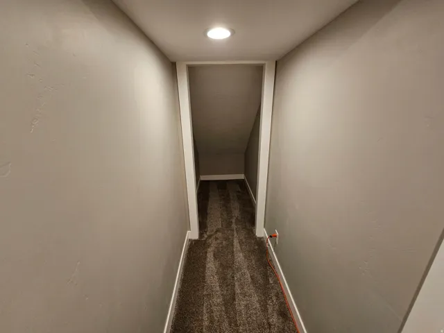 Corridor with dark colored carpet and baseboards