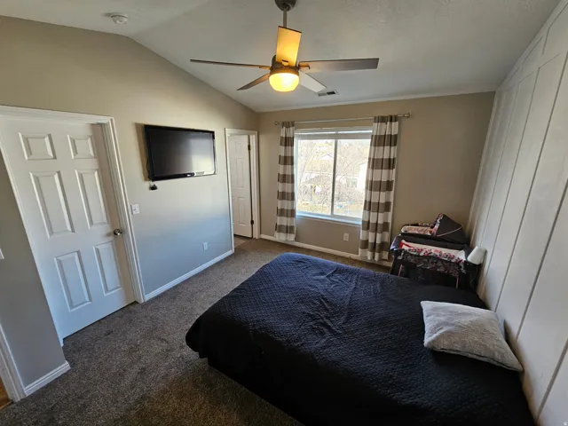 Bedroom with carpet floors, a ceiling fan, and vaulted ceiling