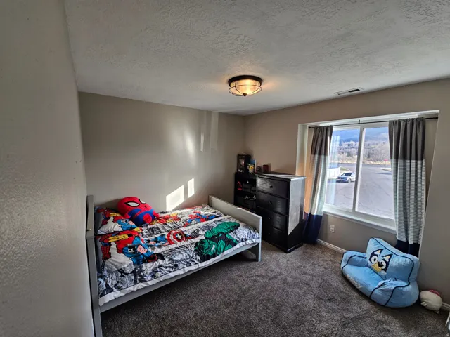 Bedroom featuring a textured ceiling and dark colored carpet