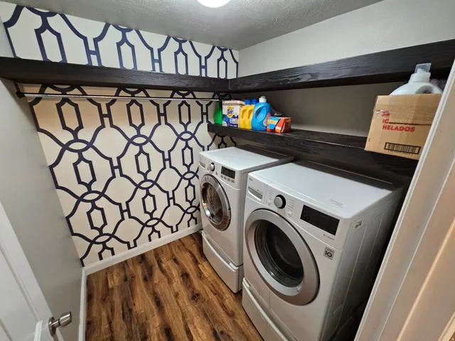 Laundry room featuring dark wood-style floors, washer and clothes dryer, and a textured ceiling