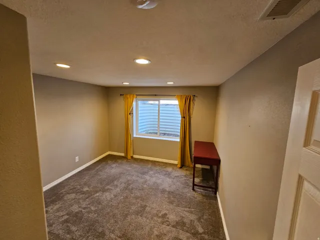 Unfurnished room featuring dark colored carpet, recessed lighting, and a textured ceiling