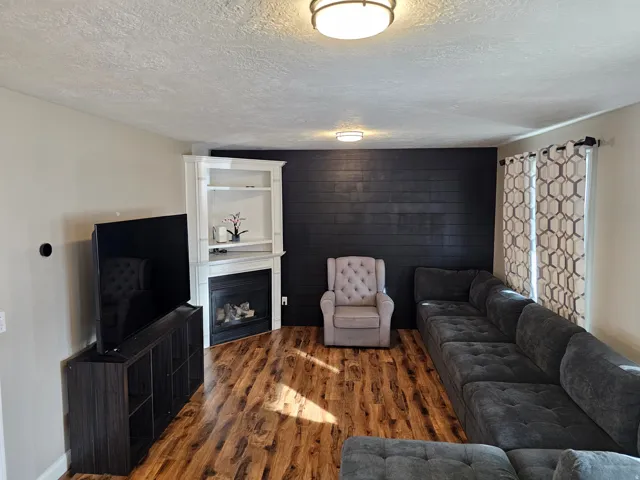 Living area featuring a textured ceiling, wood finished floors, and a fireplace
