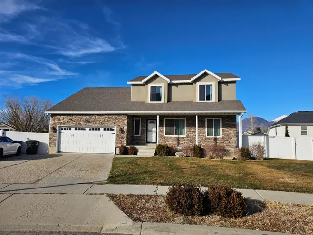 Traditional-style home featuring a porch, stone siding, driveway, roof with shingles, and an attached garage