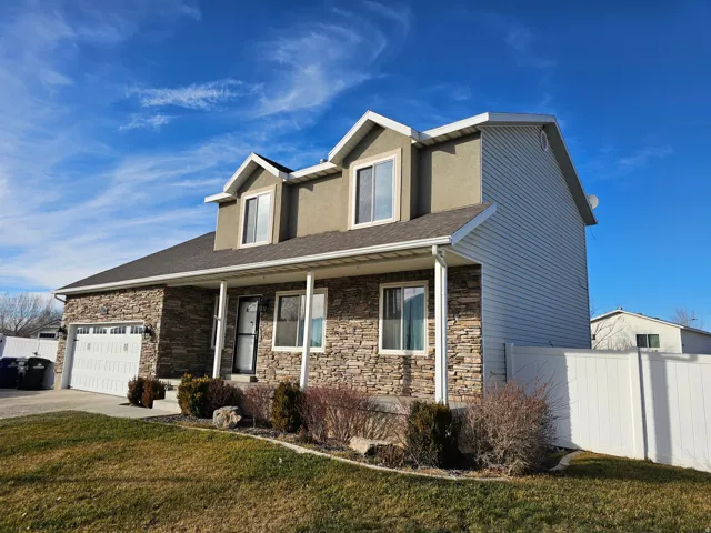 Traditional home featuring covered porch, stone siding, roof with shingles, concrete driveway, and an attached garage