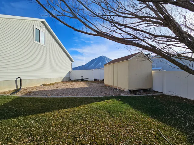 Fenced backyard with a mountain view, a storage unit, and a gate