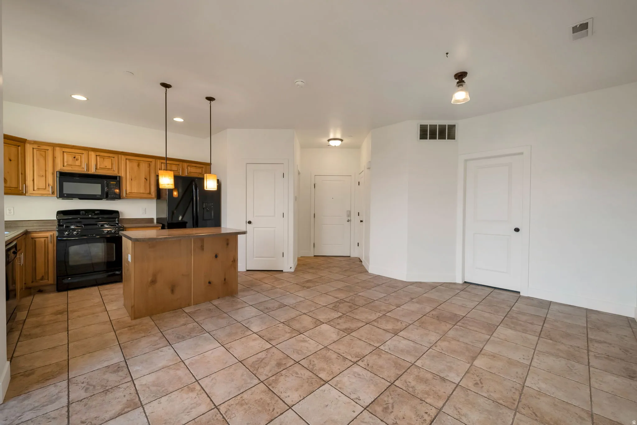 Kitchen featuring black appliances, a kitchen island, pendant lighting, recessed lighting, and brown cabinetry